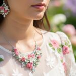 Žena v kvietkovaných šatách s náhrdelníkom a náušnicami v záhradnom prostredí.